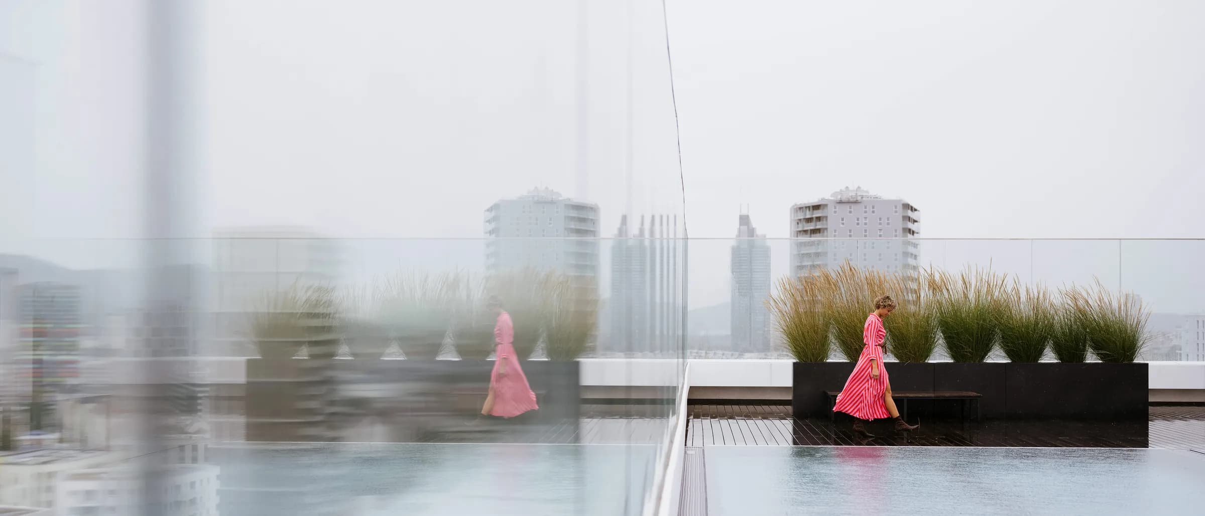 Tania geht über eine Dachterrasse, im Hintergrund die Stadt im Dunst